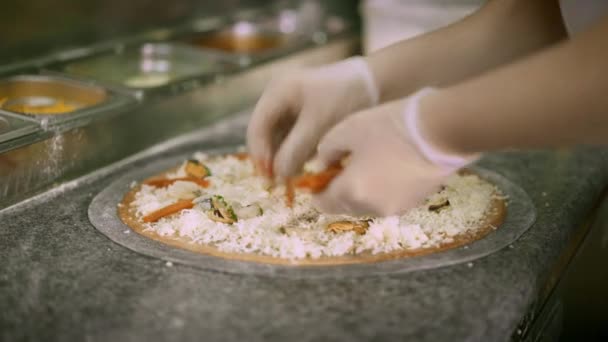 Kook vis toevoegen aan een rauw zwart pizzadeeg met kaas — Stockvideo