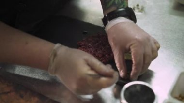 Şefin doğranmış ton balıklı bir tabağa baharat kattığı yakın plan.