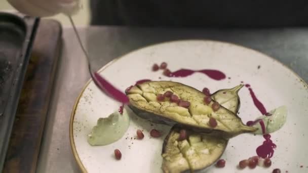 Primer plano de mano del chef macho decorando un plato con berenjena — Vídeo de stock