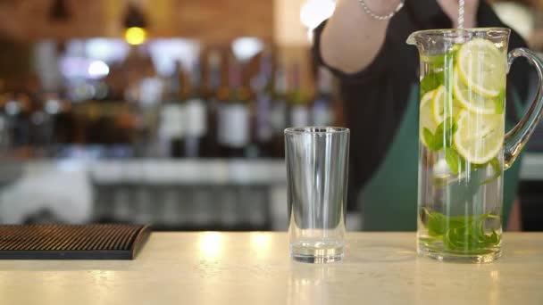 Barista mano stiring un bicchiere alto con acqua di menta limone accanto a un bicchiere vuoto in bar — Video Stock