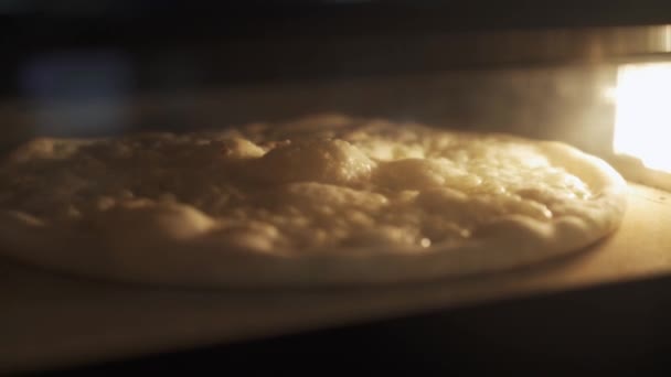 Handheld close-up van kaas pizza bakken in de oven — Stockvideo