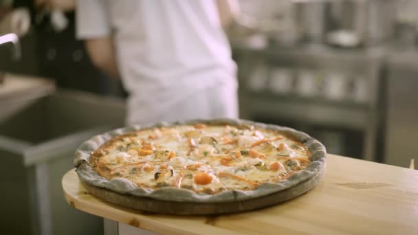 Handheld close-up shot van arugula toegevoegd aan een verse zeevruchten pizza — Stockvideo