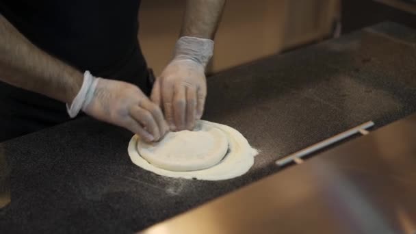 Tiro medio de mesa con las manos de chef en guantes arrugan la masa — Vídeo de stock