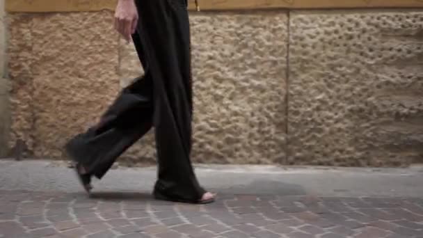 Profiel shot van vrouw benen in zwarte broek op de achtergrond van de muur met namen — Stockvideo