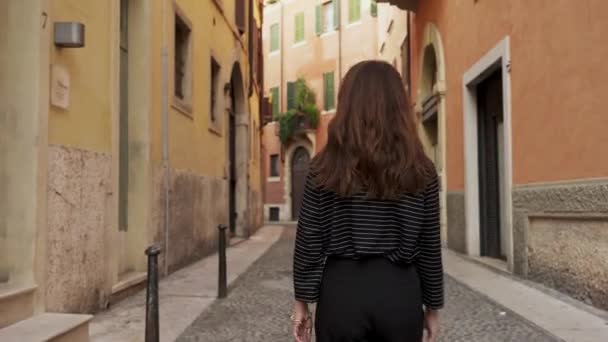 Middle shot of back of brunette woman walking on a narrow european street — 비디오