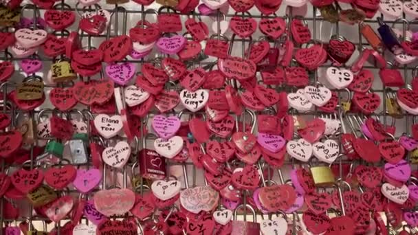 Verona, Italië - juni 2019: Metalen roze hartjes met hangsloten van minnaars aan de muur — Stockvideo