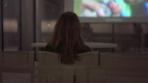 Gimbal skott av kvinna tillbaka sitter ensam i konsthallen titta på video — Stockvideo