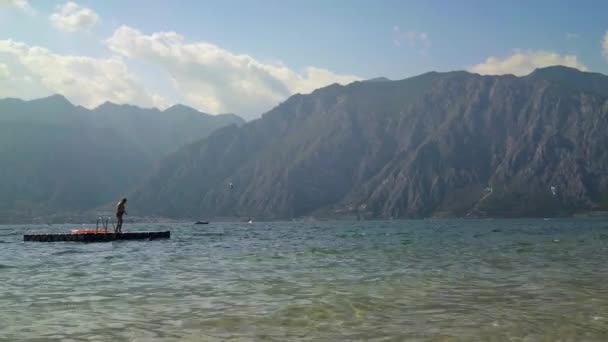 Lago de Garda - 18 de JULIO: plano ancho en tiempo real del hermoso lago de Garda en Italia. La gente está nadando, julio 18, 2019 Lago de Garda . — Vídeos de Stock