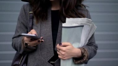 Elinde gazete tutan ve telefonda yazan bir kadın resmi.