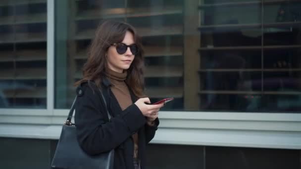 Zeitlupe einer Frau mit Handy vor Schaufenstern — Stockvideo