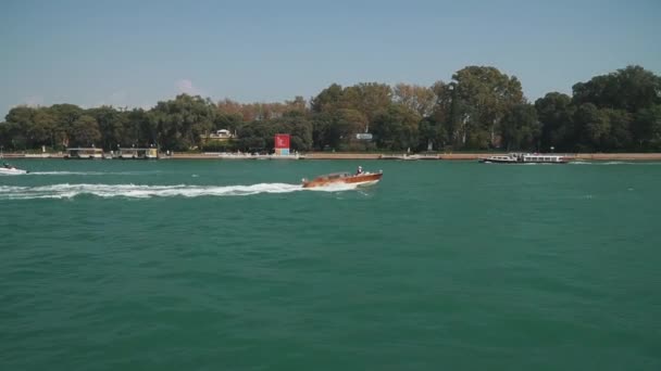 ВЕНИЦИЯ, ИТАЛИЯ - ИЮЛЬ 2019: Лодка плавает в Венеции на фоне зеленых деревьев — стоковое видео