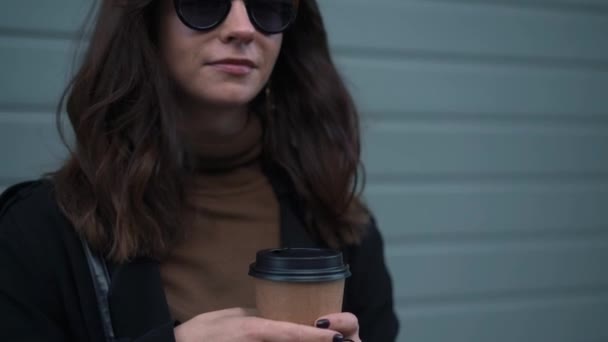 Медленное движение наклона вверх женщины снимая солнцезащитные очки улыбаясь чашкой кофе — стоковое видео