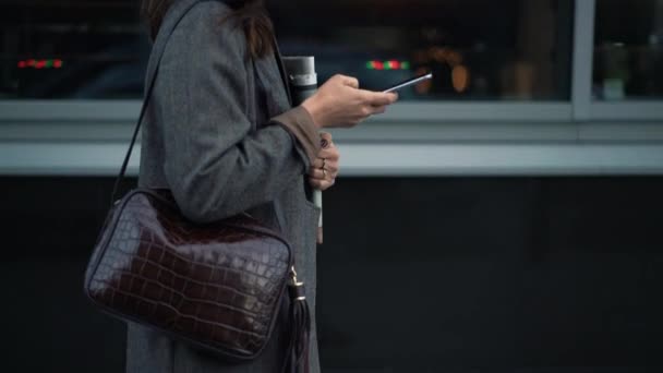 Gimbal disparo de mujer caminando con periódicos y escribiendo en el teléfono — Vídeos de Stock