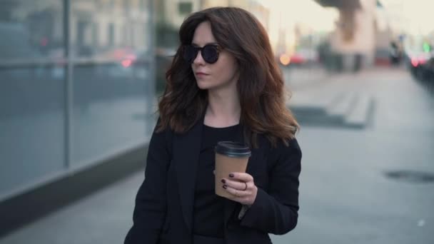 Медленное движение деловой женщины в солнечных очках с чашкой кофе — стоковое видео