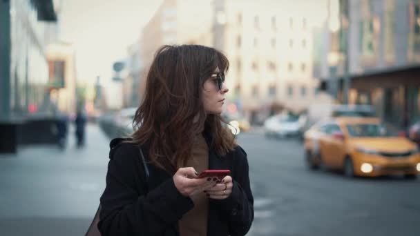 Slow motion van de vrouw met telefoon op de achtergrond van de stad weg — Stockvideo