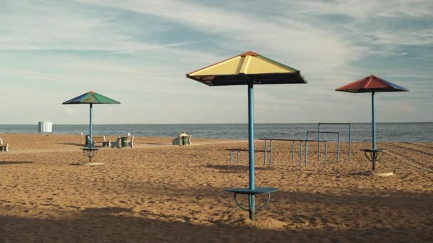 Στιγμιότυπο από ξύλινα παγκάκια στην παραλία πάνω στην άμμο στο φως του ήλιου — Αρχείο Βίντεο