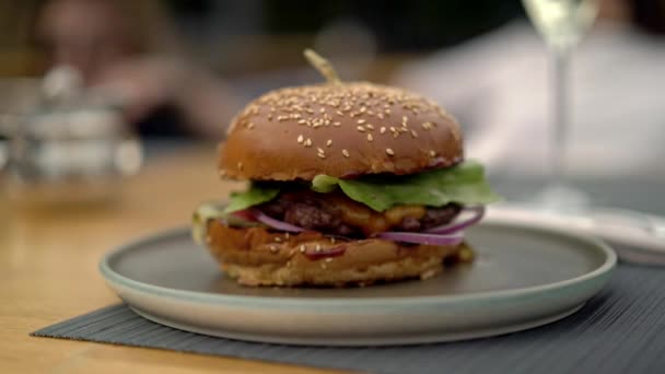 Disparo de mano de izquierda a derecha de una hamburguesa fresca en un plato — Vídeo de stock