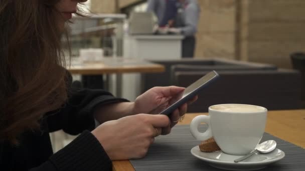 Toma de mano de la mujer escribiendo en el teléfono bebiendo una taza de café — Vídeos de Stock