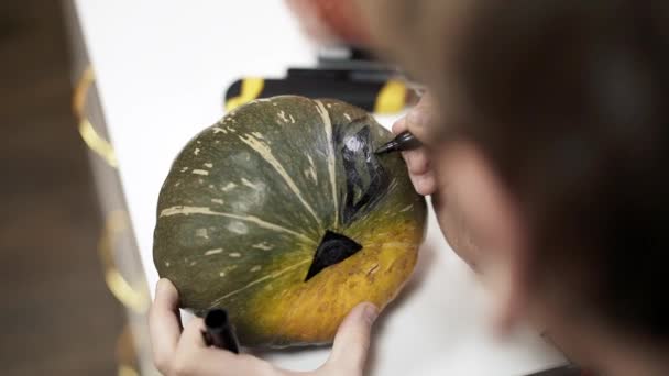 Close up of woman hands drawing on a pumpkin for halloween — Stock Video