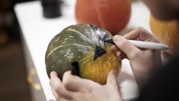 Close-up van vrouw handen tekenen op een pompoen voor halloween — Stockvideo