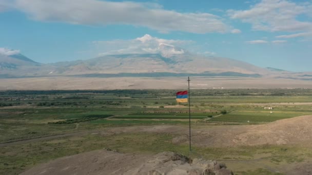 Légi drón lövés zoom ki lövés zászló integetett a dombon Örményországban — Stock videók
