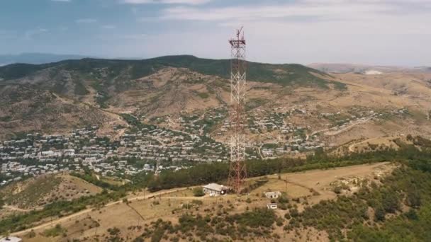 Letecký dron naklonit nahoru televizní věž na pozadí domů na kopcích domů — Stock video