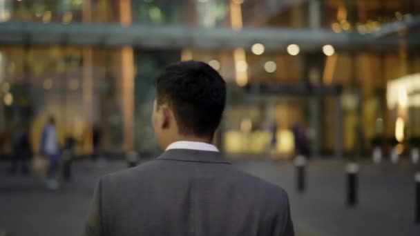 Real time portrait shot of a young businessman walking to the business building. Rear view — Stock Video