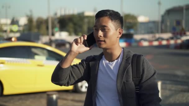 Portrait en temps réel d'un jeune Asiatique parlant de sa position au téléphone. Réunion au centre de Moscou — Video