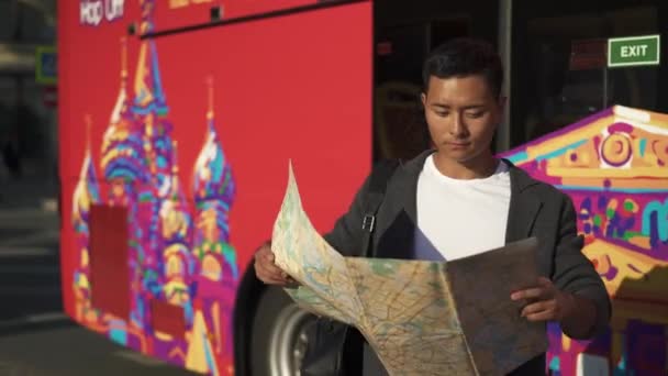 Real time portrait shot of a young Asian man getting off the bus with a map in his hands. Moscow is the capital and the most populous city in Russia. — 비디오