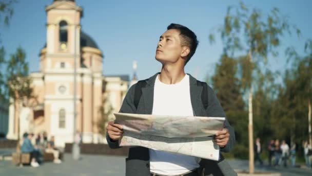 Left to right pan real time portrait shot of a young Asian man looking at a map. Tourist in Moscow.. — 비디오