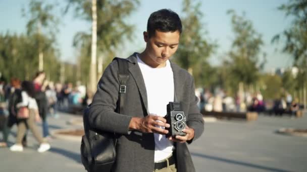 Retrato em tempo real de um jovem asiático tirando uma foto em uma câmera antiga. Moscou é a capital da Rússia . — Vídeo de Stock