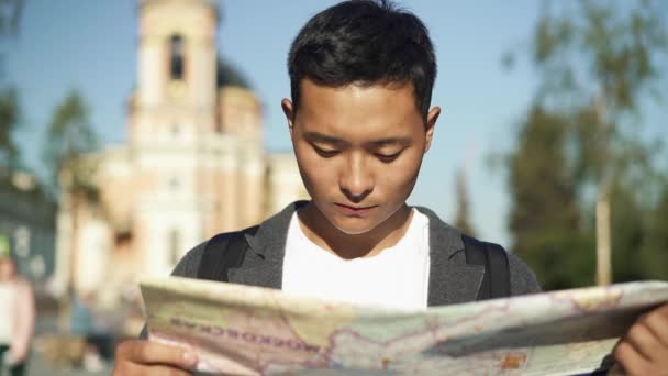 Retrato de izquierda a derecha en tiempo real de un joven asiático mirando un mapa. Turista en Moscú. Moscú es la capital de Rusia . — Vídeo de stock