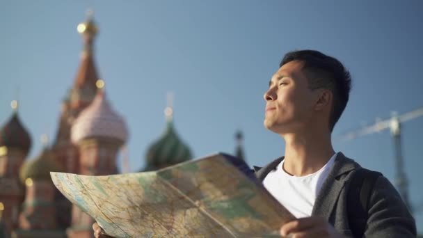 Left to right pan real time portrait shot of a young Asian man looking at a map. Tourist in Moscow. — 비디오