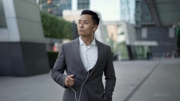 Real time shot of a young businessman dancing with headphones on the street during a break. — Stock video