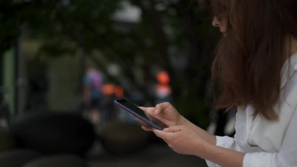 Портативный снимок женщины, печатающей по телефону на размытом фоне — стоковое видео