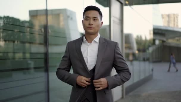 Real time portrait shot of a young businessman walking along a business building — Stock Video