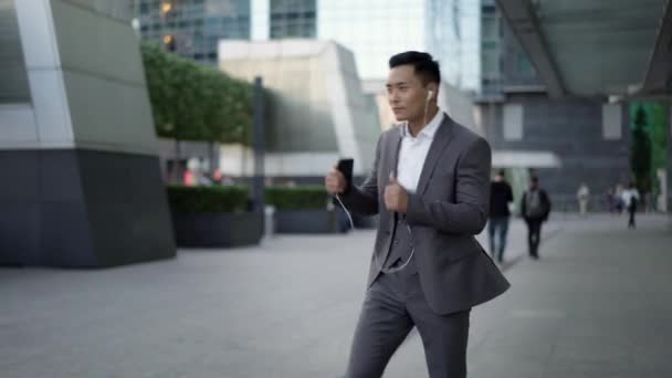 Retrato en tiempo real de un joven empresario bailando con auriculares en la calle durante un descanso — Vídeos de Stock