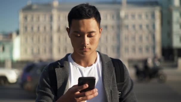 Echtzeit-Aufnahme eines jungen asiatischen Mannes, der am Telefon eine Korrespondenz führt. Moskau ist die Hauptstadt und die bevölkerungsreichste Stadt Russlands. — Stockvideo