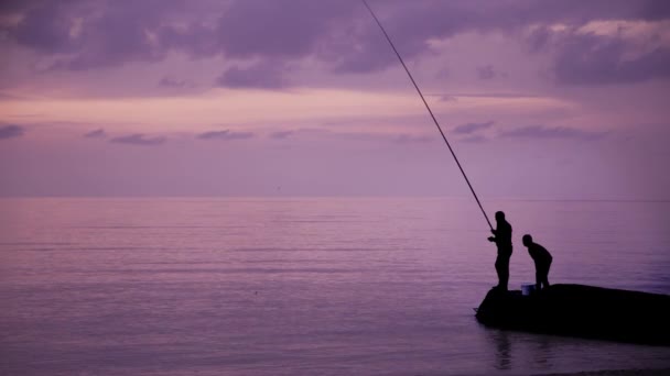 Gimbal shot of man and a child fishing on background of sea — Stock Video