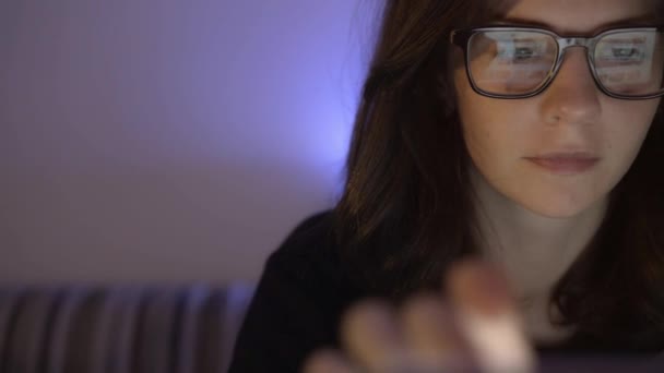 Schwenk-Aufnahme des weiblichen Gesichts, das mit Brille vor dem Computer sitzt — Stockvideo