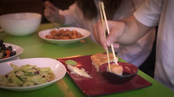 Aproape de masă cu feluri de mâncare în restaurantul asiatic, cuplu mănâncă — Videoclip de stoc