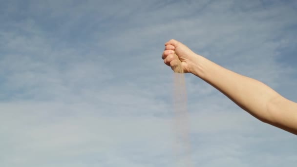Gimbal záběr ženy ruku s drolícím se pískem na pozadí oblohy — Stock video