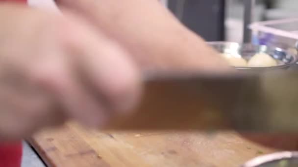 Sluiten van de kok hakken aardappelen op een houten snijplank — Stockvideo