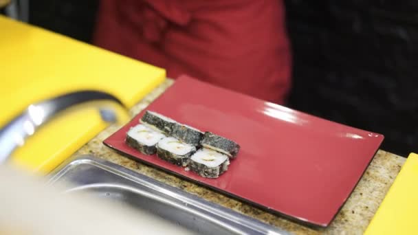 Chef hands putting a pieces of hot sushi roll on a red plate — 비디오