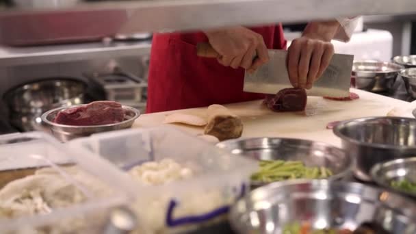 Chef-kok handen snijden vlees met groot mes in de keuken close-up — Stockvideo