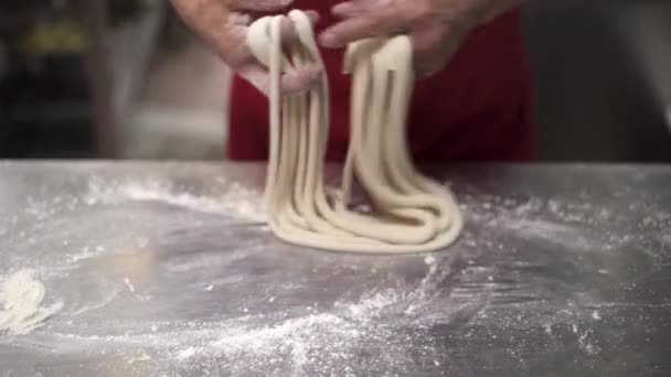 Cook rolls out spaghetti dough on a metalic table at kitchen restaurant — 비디오