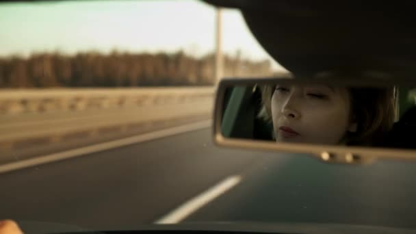 Крупним планом портрет жінки в дзеркалі під час водіння автомобіля — стокове відео