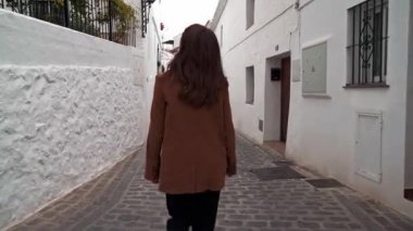 Mijas 'ın dar beyaz caddesinde yürüyen kadının görüntüsünü büyüt.