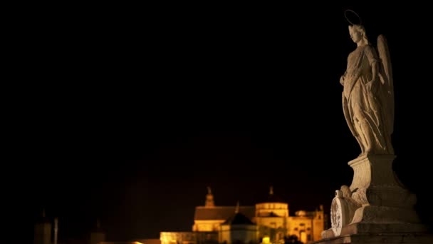 Панорамный снимок статуи Святого Фелипе ночью на римском мосту Кордовы — стоковое видео