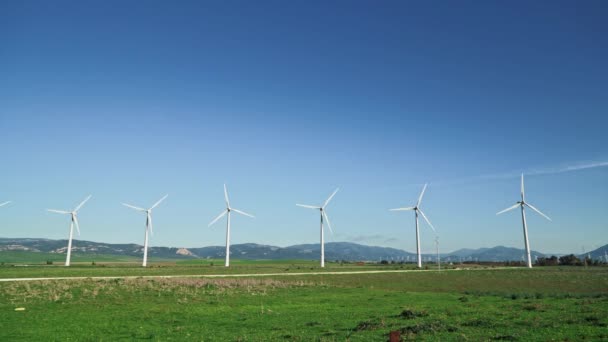 Gimbal shot van rij windmolens op achtergrond van bergen in Spanje — Stockvideo